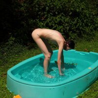 Small thin girl peeing next to paddling pool